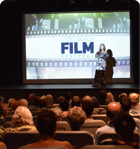 Vero Beach Film Festival event with audience and presenter on stage.